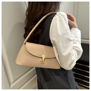 Close-up of minimalist pink shoulder bag featuring a gold cylindrical twist lock buckle