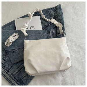 Detail of white PU handbag showing cloud-shaped pleated handle and detachable shoulder strap