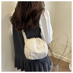 Detailed view of cream corduroy crossbody bag with double zippers and wide strap