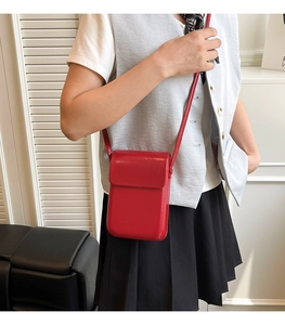 Vertical red leather mini crossbody phone bag shown on model with polished flap closure
