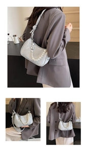 Detail of silver metallic bag with decorative pearl and heart charm chain link