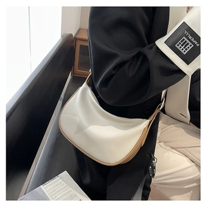 Detail of cream PU leather dumpling bag with brown trim styled on a black blazer