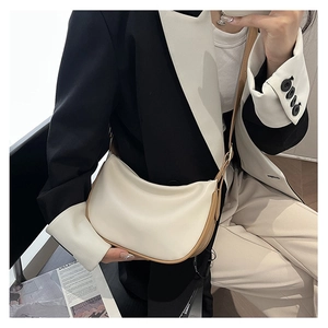 Chic cream hobo bag with brown trim shown on a model in professional attire