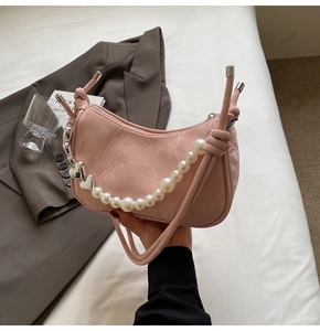 Detail of pink hobo bag with textured leather, large pearl chain, and heart charms