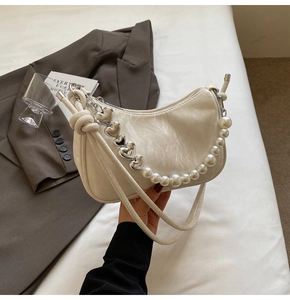 Detail of cream white half-moon bag with large pearl strap and silver heart charms