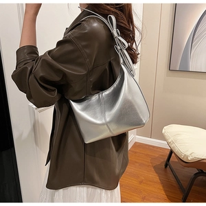 Détail du sac demi-lune argenté avec nœud latéral et texture métallique brillante