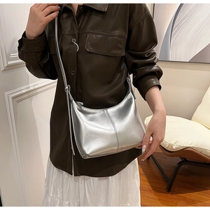 Detail of silver crescent leather bag with metallic finish and vertical double stitching
