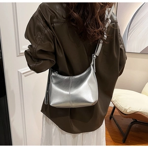 Close-up of metallic silver bucket bag with double stitching detail and long shoulder strap