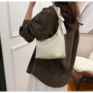 Sac seau chic en similicuir crème avec un détail de nœud délicat sur la bandoulière