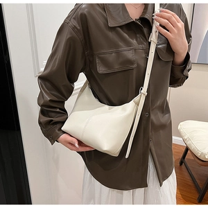 Détail d'un sac demi-lune crème minimaliste avec coutures verticales et bandoulière