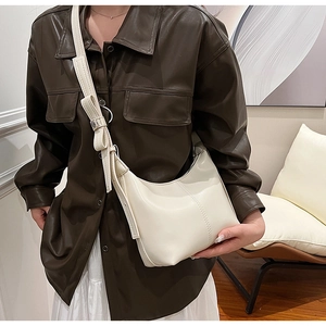 Detail of off-white hobo bag showing the leather bow accent and fine vertical stitching