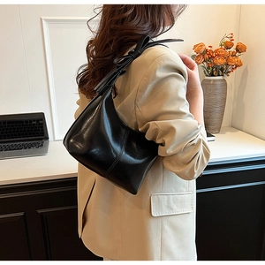 Détail du sac hobo noir brillant en forme de lune avec nœud sur la bandoulière