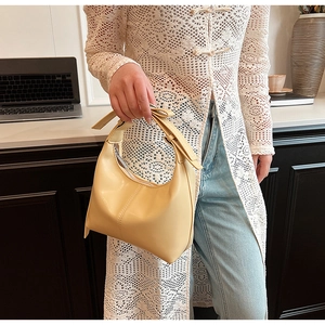 Sac hobo jaune pâle avec coutures verticales présenté dans un cadre élégant