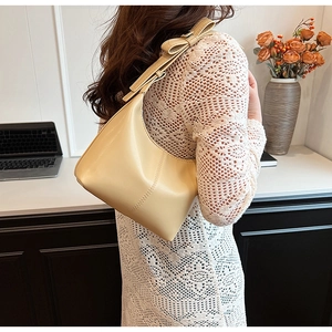 Detail of beige shoulder bag with bow knot on strap and elegant vertical stitching