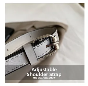 Detail of adjustable leather shoulder strap with silver buckle and white stitching