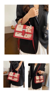 Close-up of red plum blossom embroidery on beige fabric bag with silver H-shaped lock