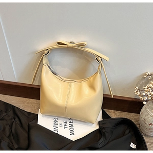 Detail of a creamy beige PU leather hobo bag featuring decorative bow and zipper closure
