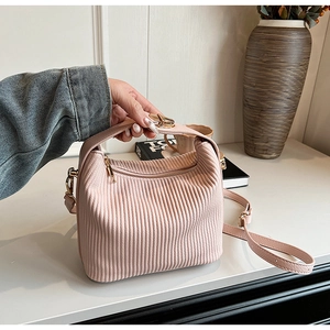 Détail du sac seau rose plissé avec texture verticale et fermeture éclair dorée brillante
