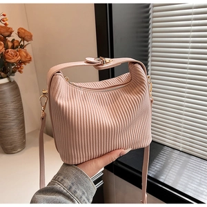 Détail d'un sac à main plissé rose clair avec texture lisse et fermeture éclair en métal doré