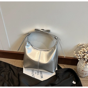 Détail du sac hobo argenté métallisé avec un nœud décoratif sur la poignée haute