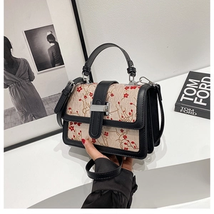 Detail of floral fabric pattern and black leather stitching on a retro square bag
