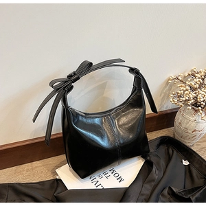 Detail of black oil wax PU hobo bag with oversized bow and vertical stitching
