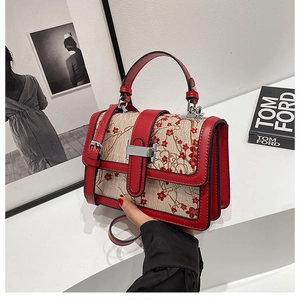 Detail of floral embroidery on a vintage style square handbag with red leather trim