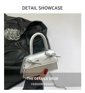 Detail of silver mini bag with double bows and chain strap against a dark backdrop