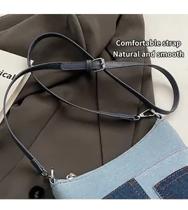 Detail eines verstellbaren blauen Denim-Schultergurts mit silberner Metallschnalle an Tasche