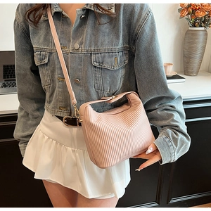 Détail du sac à bandoulière plissé rose clair avec boucle dorée et texture en cuir souple
