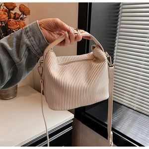 Détail du sac à bandoulière beige plissé avec fermeture éclair dorée et texture rayée