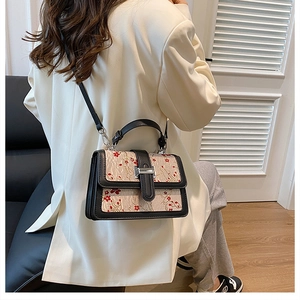 Close-up of vintage style floral embroidery handbag with leather flap and strap details