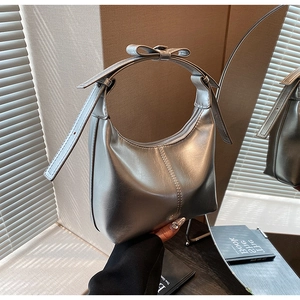 Gros plan du sac hobo argenté métallisé avec détail de nœud papillon et bords arrondis