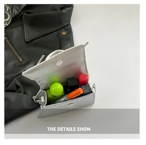 Mini silver crossbody bag interior showing storage for lipstick and perfume bottles