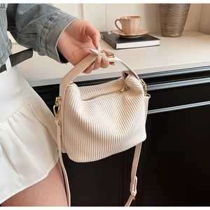 Détail du sac plissé crème montrant la texture velours et les finitions métalliques dorées