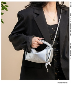 Détail du sac à main plissé argenté avec imprimé floral et bandoulière en chaîne