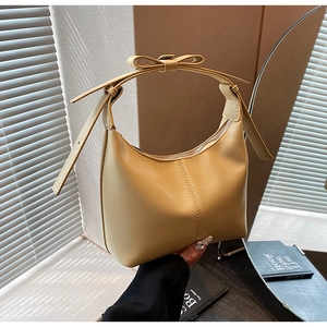 Gros plan sur un sac hobo jaune pâle avec un nœud élégant et une couture verticale