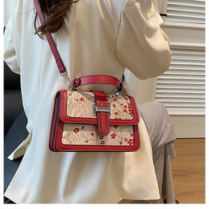 Woman carrying a vintage floral embroidery crossbody bag with red leather trim