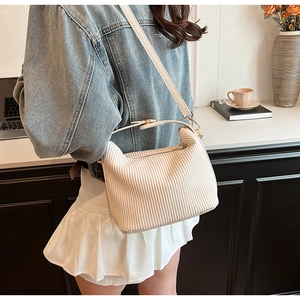 Détail du sac à main en velours côtelé plissé crème avec textures douces et boucles dorées