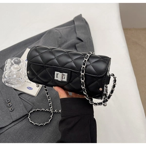 Détail du sac cylindrique noir matelassé avec fermoir rotatif argenté et bandoulière