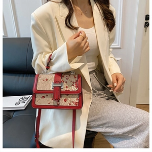 Elegant red plum blossom jacquard handbag shown being worn with a white suit