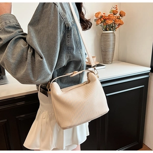 Détail d'un sac à bandoulière plissé blanc cassé avec crochets dorés sur veste en jean