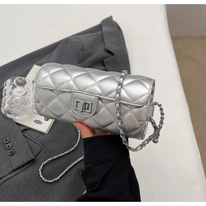 Détail du sac cylindre argenté matelassé avec bandoulière chaîne et fermoir rotatif