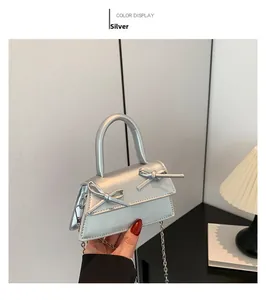 Detail of silver mini handbag with metallic finish and cute bow accents on the front