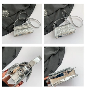 Macro view showing silver crocodile embossed texture and metal hardware of the handbag