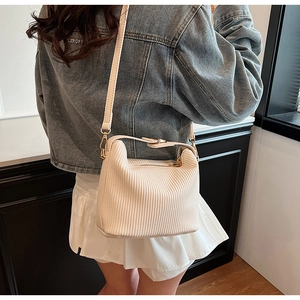 Détail d'un sac bandoulière plissé blanc crème avec texture côtelée et détails dorés brillants