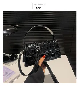Close-up of black crocodile embossed glossy leather handbag with metallic clasp