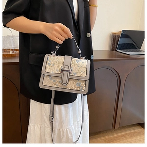 Detail of floral jacquard handbag with PU trim and silver buckle shown with long strap