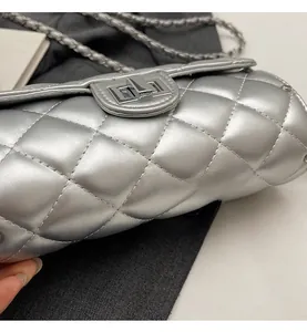 Détail macro d'un sac argenté matelassé avec fermoir rotatif métallique et bandoulière