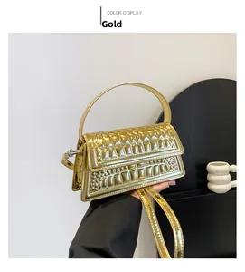 Detail of the golden faux crocodile texture and glossy finish on the structured handbag